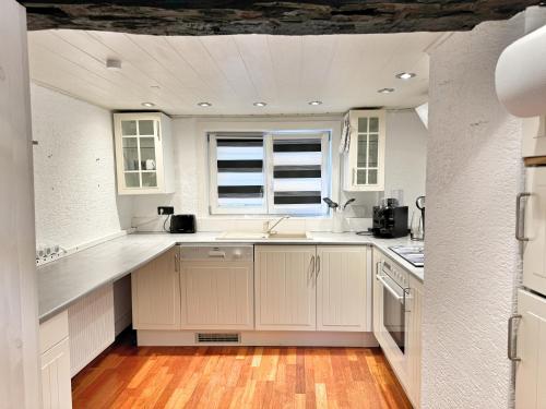 a kitchen with white cabinets and a window at Fachwerkhaus im Landhausstil in Staufenberg