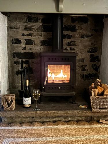 a fireplace with a stove with a glass of wine at The Hideaway Holmfirth in Holmfirth