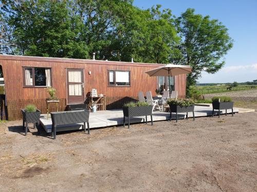 a tiny house with chairs and an umbrella at Donnas Place in Sint Jacobiparochie