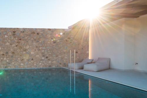 a pool with a couch and chairs next to a wall at Noema Luxury Retreat Villas - Adults only in Kos Town
