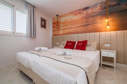 a bedroom with a large white bed with red pillows at Ponderosa 611, Las Americas, one bedroom apartment with large terrace and ocean view, next to Siam Park in Playa Fañabe