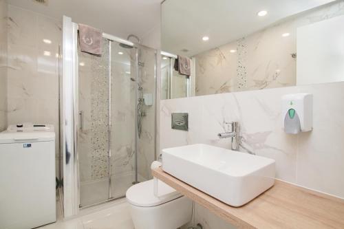 a white bathroom with a sink and a shower at Ponderosa 611, Las Americas, one bedroom apartment with large terrace and ocean view, next to Siam Park in Playa Fañabe