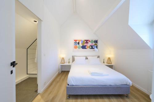 a white bedroom with a bed and a staircase at Le cottage de la Verte Voie in Wavre