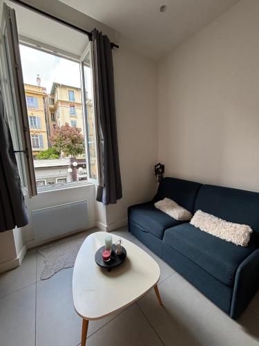 un salon avec un canapé bleu et une table dans l'établissement 1 Bedroom Flat in heart of nice, à Nice