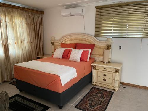 a bedroom with a bed with red and white pillows at Ben Kalulu House in Mangeti