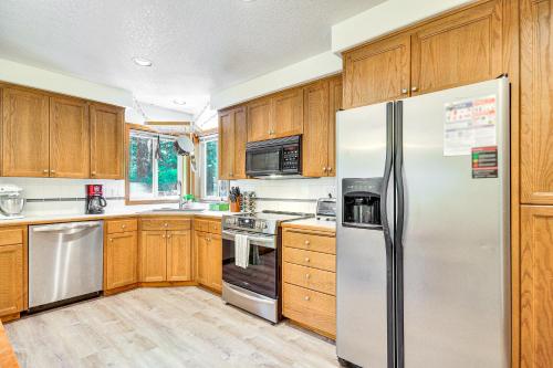 a kitchen with wooden cabinets and a stainless steel refrigerator at Rhododendron Retreat with Hot Tub Steps to River! in Rhododendron