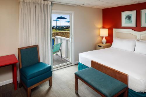 a hotel room with a bed and two chairs and a balcony at Pleasant View Inn in Westerly