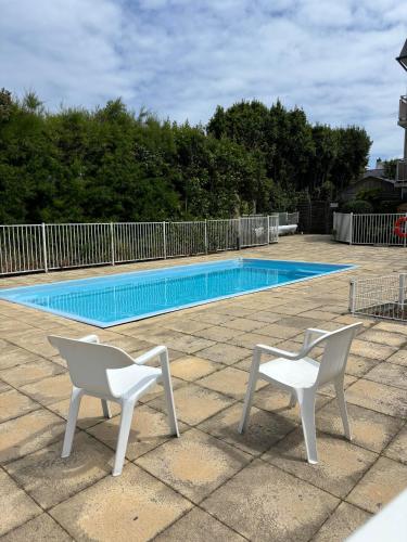 - deux chaises blanches installées à côté de la piscine dans l'établissement Appartement studio 4 personnes dans résidence avec piscine, à Quiberon