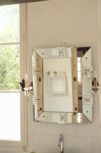 espejo en una pared sobre un lavabo en el baño en La petite maison, en Crépy-en-Valois