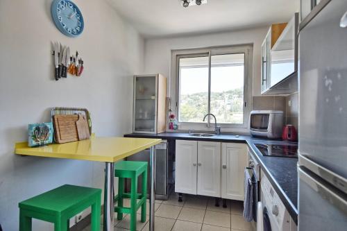 une cuisine avec une table jaune et des tabourets verts dans l'établissement Grand T2 avec une magnifique vue mer et JO, à Marseille