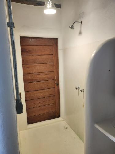 a bathroom with a wooden door in a room at Suíte Caju - Conforto e Exclusividade em Trancoso in Trancoso