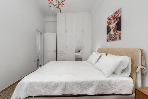 a white bedroom with a bed and a painting on the wall at Aphrodites Place in Messini