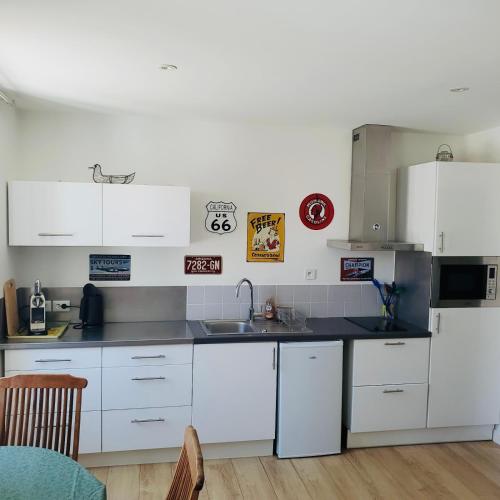 une cuisine avec des armoires blanches et un évier dans l'établissement LES MARIETTES, à La Rochelle