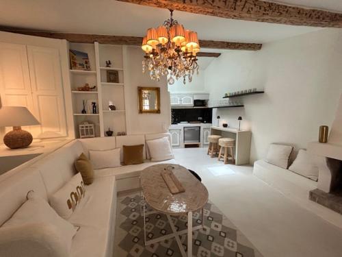 ein Wohnzimmer mit einem Kronleuchter, einem Sofa und einem Tisch in der Unterkunft Maison Saint Tropez in Saint-Tropez