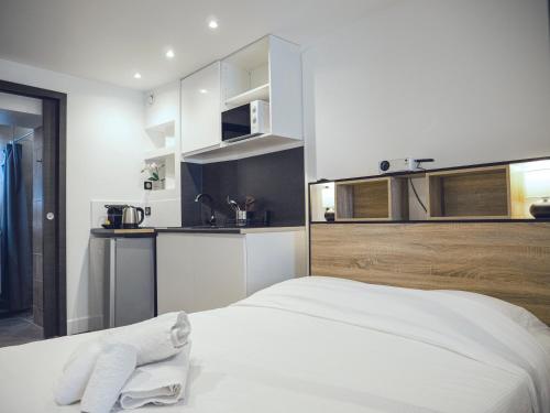 Cet appartement comprend une chambre avec un lit blanc et une cuisine. dans l'établissement Studio contemporain hypercentre, à Nancy