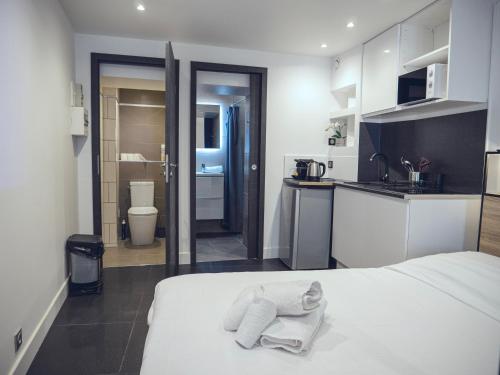 Cet appartement comprend une chambre avec un lit blanc et une cuisine. dans l'établissement Studio contemporain hypercentre, à Nancy