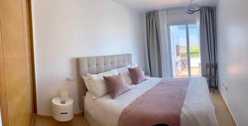 a bedroom with a bed with pink pillows and a window at Casa Carlitos Las Terrazas de La Torre Golf Resort in Murcia