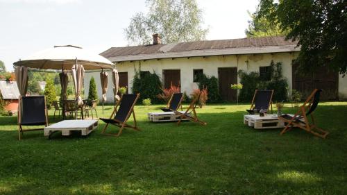 a group of lawn chairs and an umbrella in front of a house at Apartamenty Rycerskie in Inowłódz