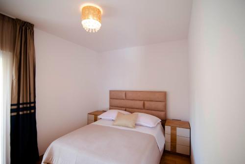 a bedroom with a bed and a chandelier at Two bedroom apartment Karmen with pool in Sinj