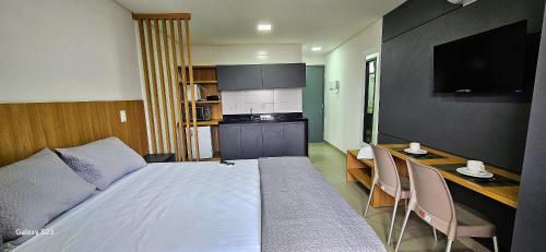 a bedroom with a bed and a desk and a kitchen at Flats Tramonto - By EasyHost in João Pessoa