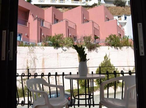 a table and chairs on a balcony with a pink building at Argiro's apartment at Agia Galini in Agia Galini