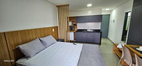 a bedroom with a large bed and a kitchen at Flats Tramonto - By EasyHost in João Pessoa