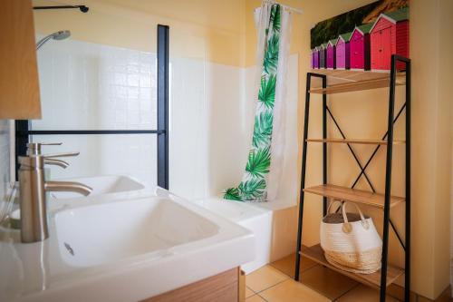 La salle de bains est pourvue d'un lavabo blanc et d'une étagère. dans l'établissement Maison de vacances quartier Arago Les Sables - 6 personnes, à Les Sables-dʼOlonne