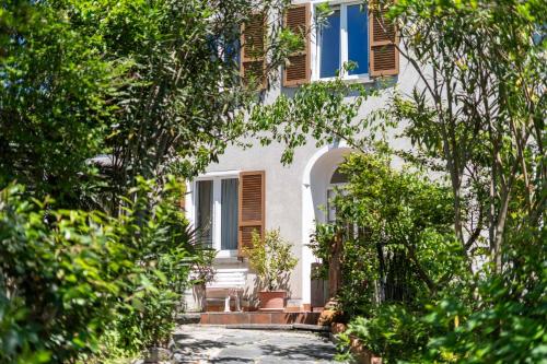 a white house with wooden shuttered windows and trees at Easy Stay by Hotel La Perla in Ascona