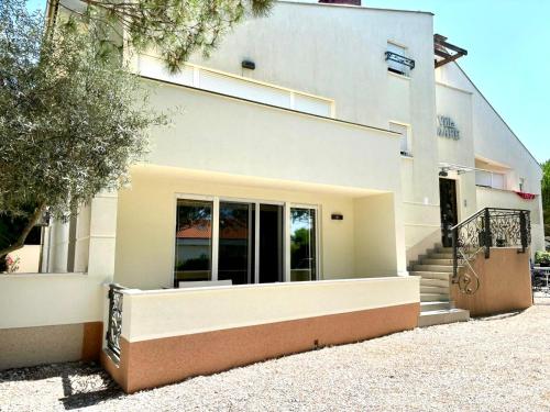 a white building with stairs in front of it at Delux 4 Stars Apartment Ariadne - 1 Min from Beach in Soline