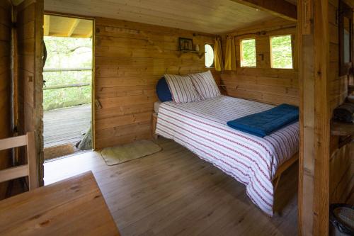 une chambre dans une cabane en rondins avec un lit dans l'établissement Les Noctam'bulles - Cabanes dans les arbres, à Saint-Pierre-Azif
