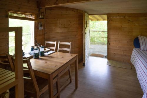 - une salle à manger avec une table en bois et un lit dans l'établissement Les Noctam'bulles - Cabanes dans les arbres, à Saint-Pierre-Azif