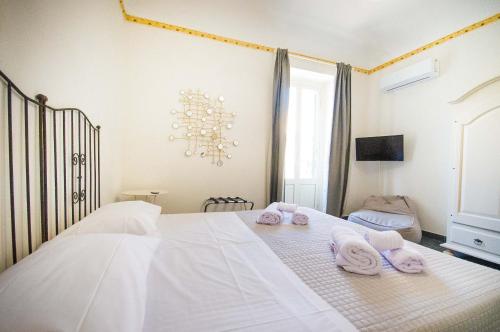 a bedroom with a white bed with towels on it at San Domenico Appartaments in Noto