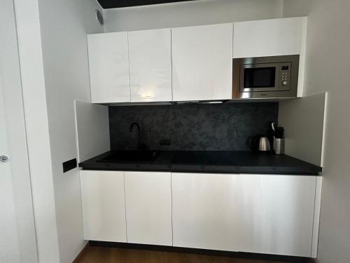 a kitchen with white cabinets and a microwave at BB Hotels Aparthotel Isola in Milan