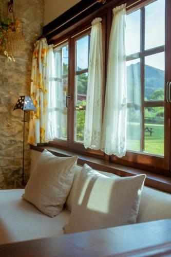a bed with pillows in a room with a window at El Molino de Bonaco in San Vicente de la Barquera
