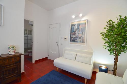 a living room with a white chair and a plant at Appartamento in centro 5 minuti dal mare in Brolo