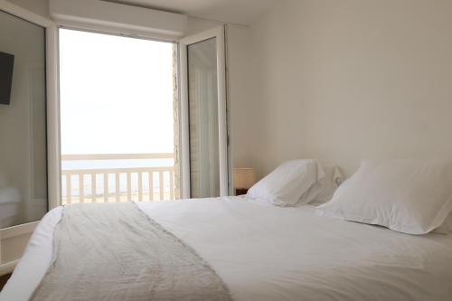 a bedroom with a white bed with a large window at Le Clos Normand in Saint-Aubin-sur-Mer