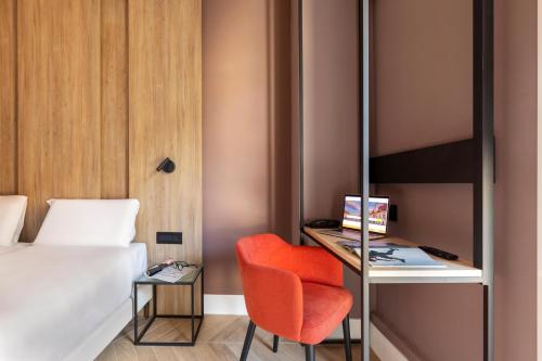 a room with a bed and a chair and a desk at B&B Hotel Genova City Center in Genova