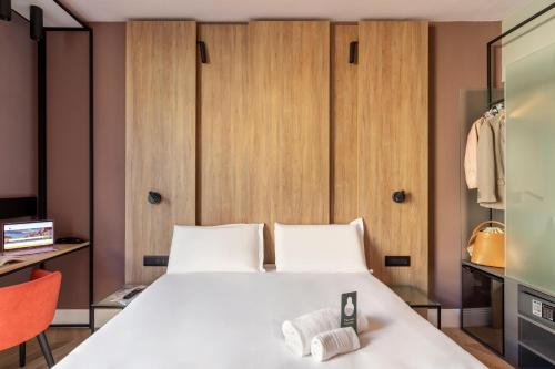 a bedroom with a large white bed and a orange chair at B&B Hotel Genova City Center in Genova