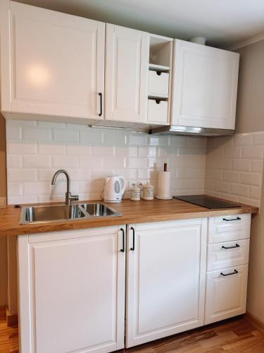 a kitchen with white cabinets and a sink at Striķu15 - Dzīvoklis ar terasi in Saldus