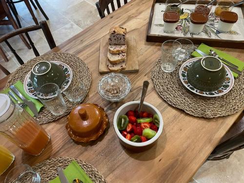 a wooden table with food and a bowl of fruit at Les Tables de La Rousse in La Fouillade