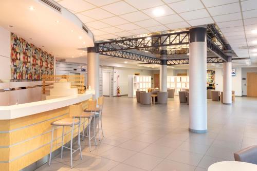a large lobby with a bar and stools at B&B Hotel Cherasco Langhe in Cherasco