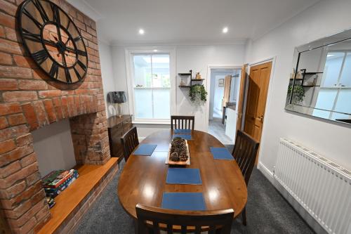 a dining room with a wooden table and a brick wall at Wisteria Cottage Town Centre FREE PARKING in Stratford-upon-Avon