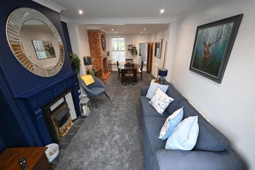 a living room with a blue couch and a mirror at Wisteria Cottage Town Centre FREE PARKING in Stratford-upon-Avon