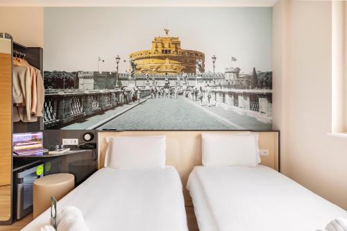 two beds in a room with a picture of a building at B&B Hotel Roma Fiumicino Aeroporto Fiera 2 in Fiumicino