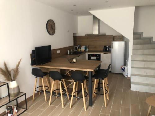 - une cuisine avec une table en bois et des tabourets de bar dans l'établissement Maison de village rénovée et équipée, à Saint-Nazaire-le-Désert