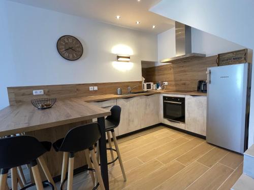 une cuisine avec un comptoir et une horloge au mur dans l'établissement Maison de village rénovée et équipée, à Saint-Nazaire-le-Désert