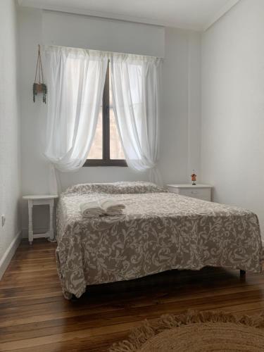 a bedroom with a bed and a window with white curtains at piso céntrico en Bilbao in Bilbao