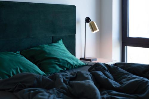an unmade bed with a green blanket and a lamp at Penthouse apartment with an amazing view in Tallinn