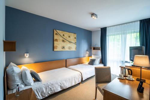 a bedroom with a bed and a desk with a computer at Hotel Nawigator Szczawnica in Szczawnica