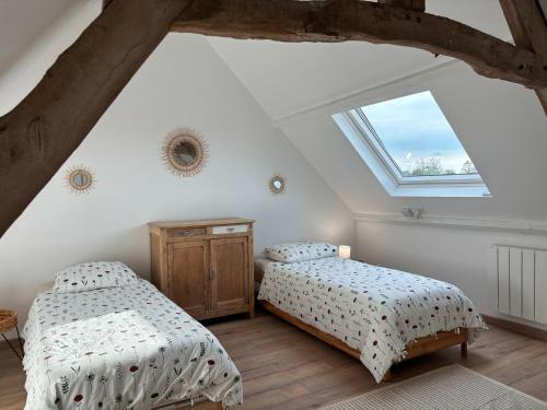 - 2 lits dans une chambre mansardée avec fenêtre dans l'établissement La Grange Des Guesdons, à Ellon